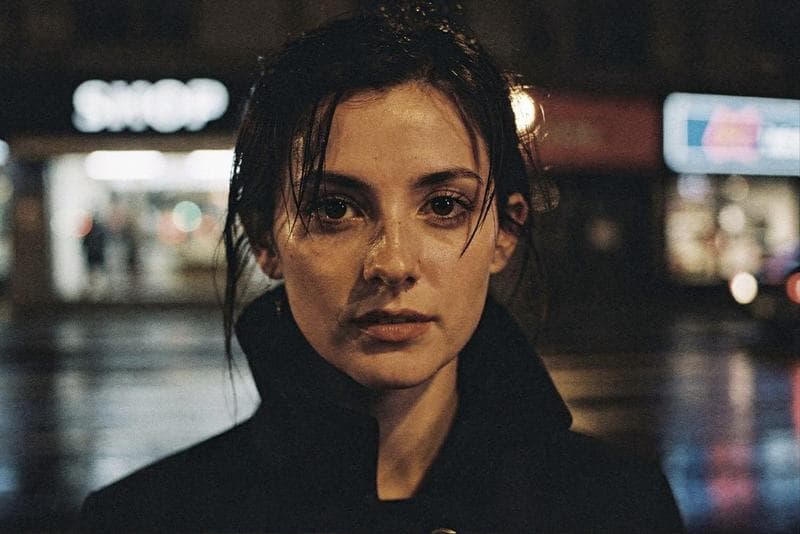 Close-up portrait of a woman on a rain-wet city street at night, generated from the shared brief